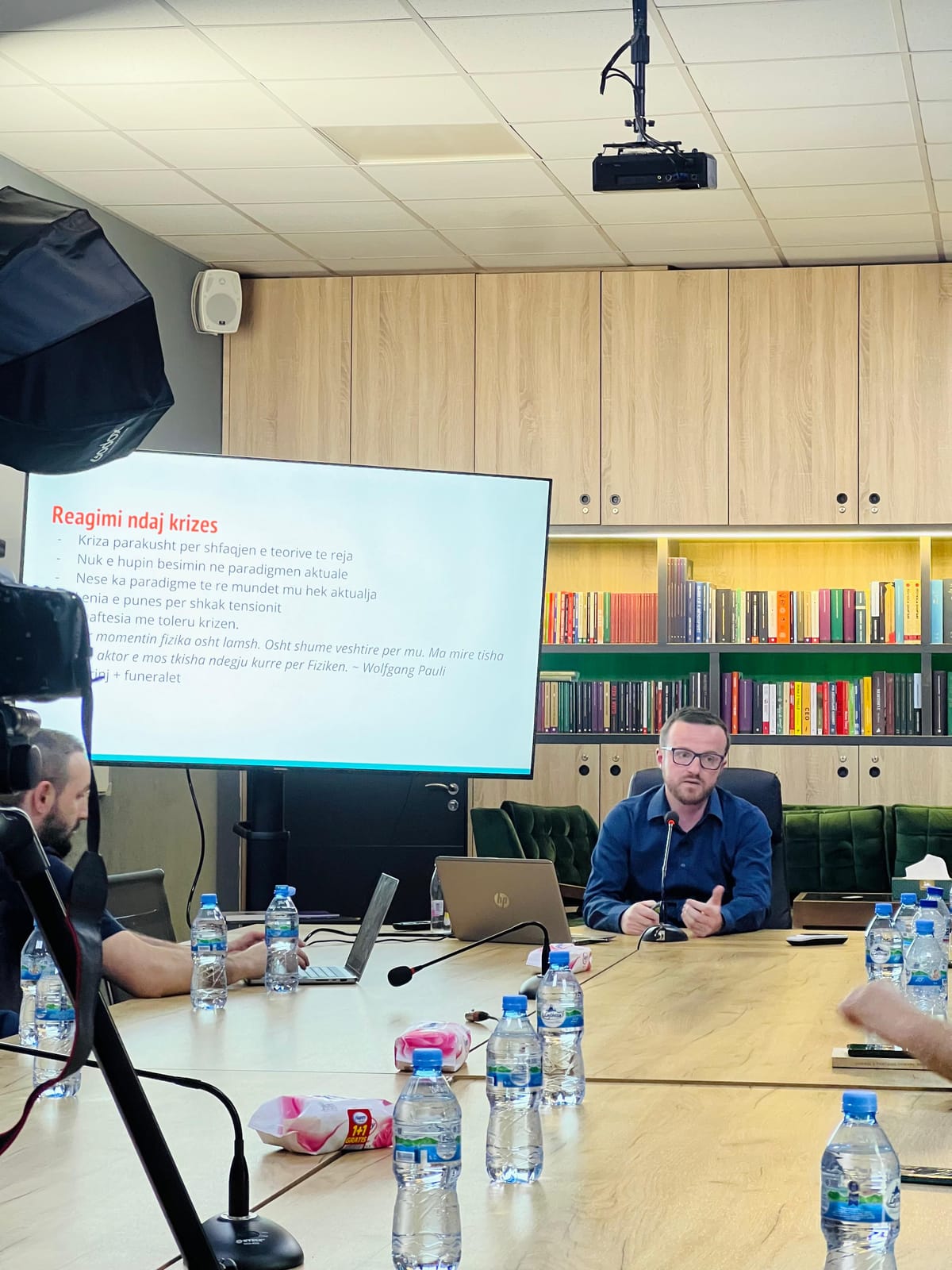 Folësi duke prezantuar pranë ekranit me slajdin e temës